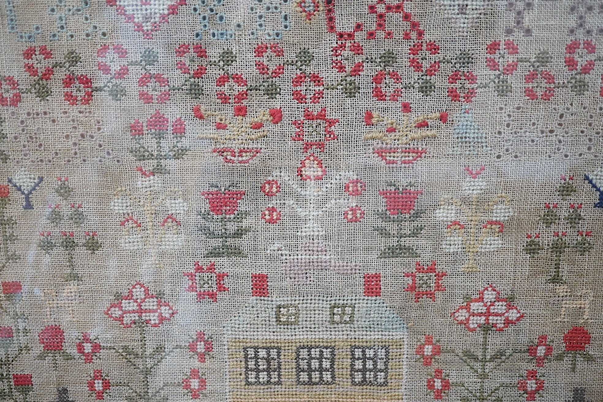 A large framed cross stitch sampler, by Helen Rae, dated 1851, worked mostly in red and green, with an ornate floral border around alphabet letters and numerals, large button hole letters and motifs, with a large central